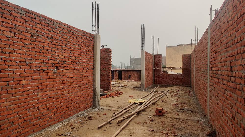 Red brick walls built between cast RCC columns, with reinforcement projecting above for the next lift.