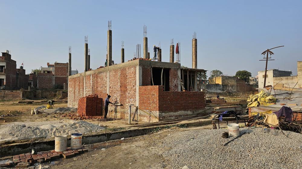 Wider view of the site with brickwork up to lintel level and column steel projecting above the slab.