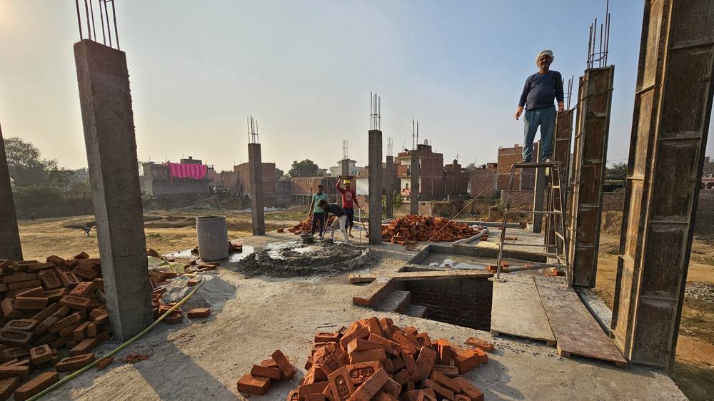 Columns risen from the footings to plinth level, with the sump excavation still open and brick stacked on site.