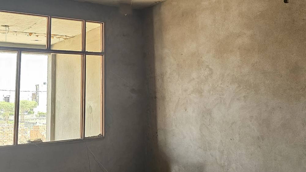 A plastered room with a framed window opening, ready for the owner's finishing contractor.