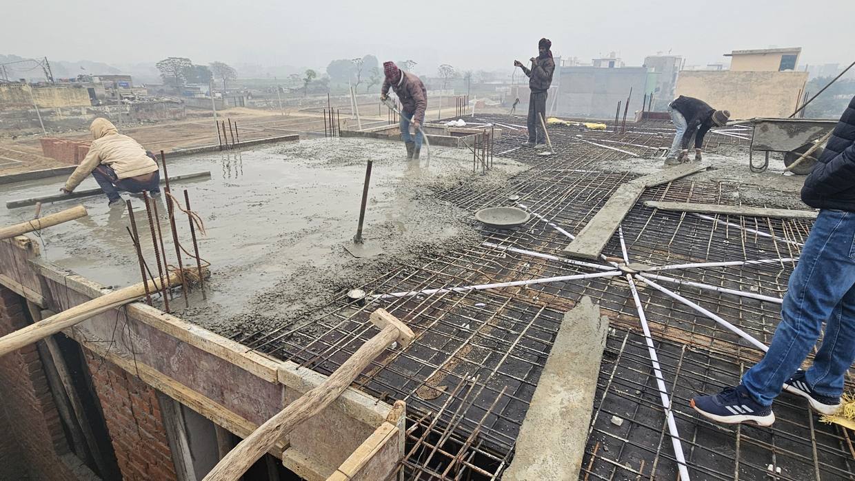 Workers placing and screeding concrete across the slab reinforcement during a continuous pour on a winter morning.